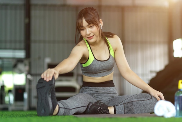 Привлекательная женщина фитнеса, растягивая ноги для подготовки к тренировке в тренажерном зале разминки и остыть