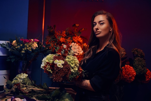 Attractive flower shop owner is posing for photographer with nice bouquet in hands.