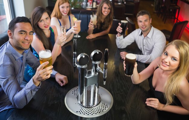 Attractive friends raising glasses up smiling at camera