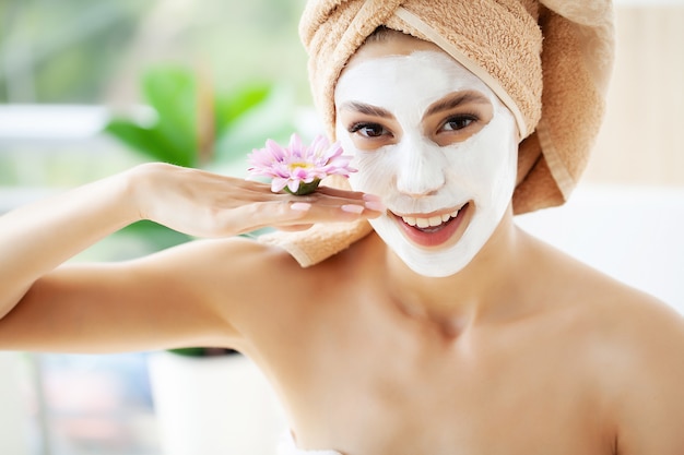 Attraente donna divertente con una maschera di argilla sul viso.