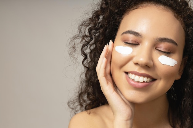 Attractive girl applies cream on her face closeup