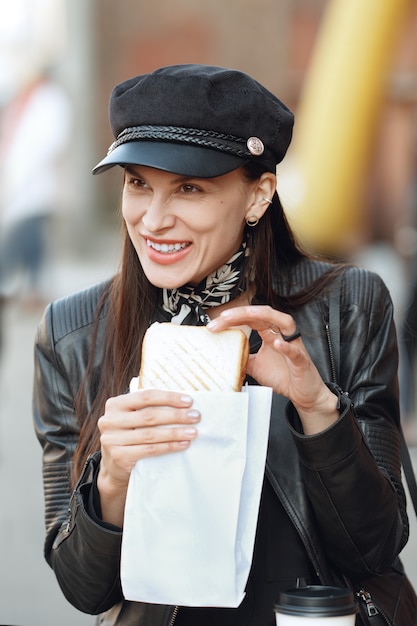 Ragazza attraente che mangia panino per strada