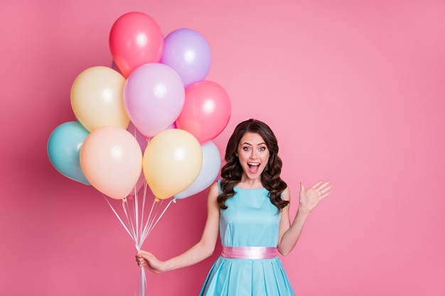 attractive girl holding in hand bunch helium balls isolated over pink pastel color background