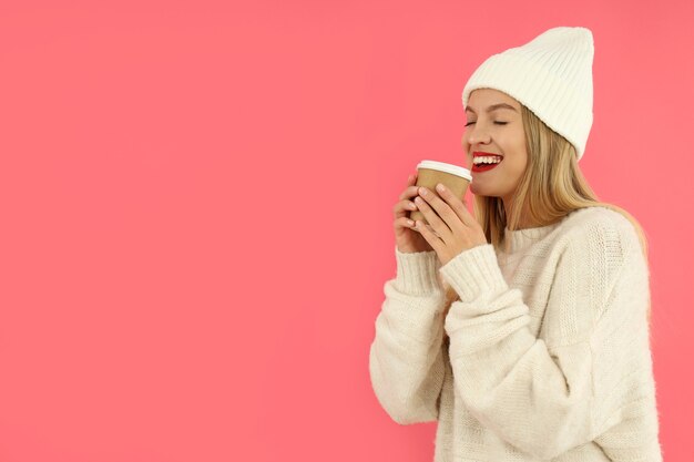 Attractive girl holds paper cup on pink background.