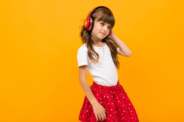 Attractive girl listens to music on orange