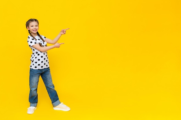 An attractive girl points to the advertisement and smiles beautiful fashionable clothes on the child