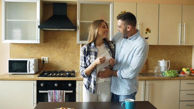 Attractive girl shows pregnancy test result to her boyfriend and surpise him at the kitchen