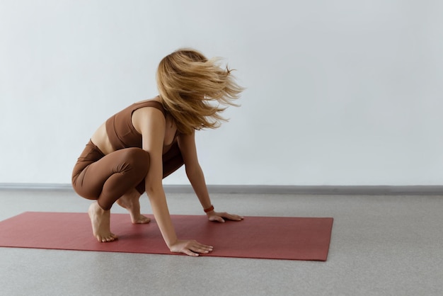 An attractive girl sits on a yoga mat Slim body and health careCrane Pose Bakasana