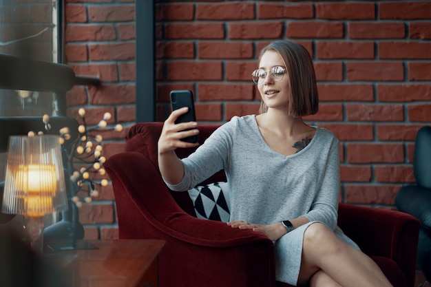 Attractive girl sitting in a red cozy chair