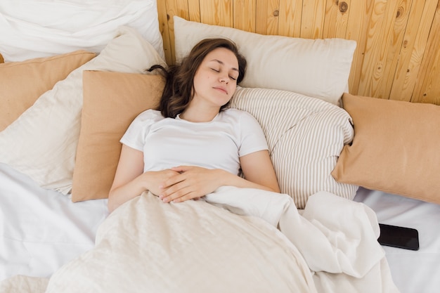 An attractive girl sleeps in a bed in her modern bright apartment