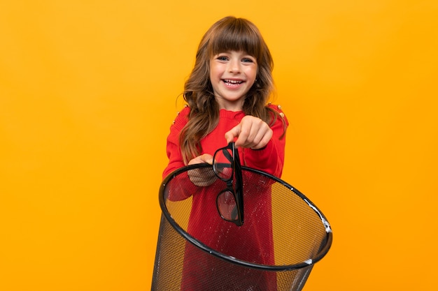 Attractive girl throws glasses for vision in the bin on a yellow background.