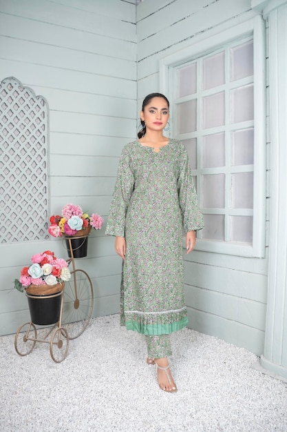 Photo attractive girl wearing floral dress at indoor location with flowers for fashion shoot