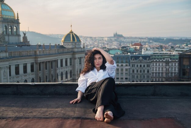 Foto una ragazza attraente con una maglietta bianca e un cardigan sul tetto