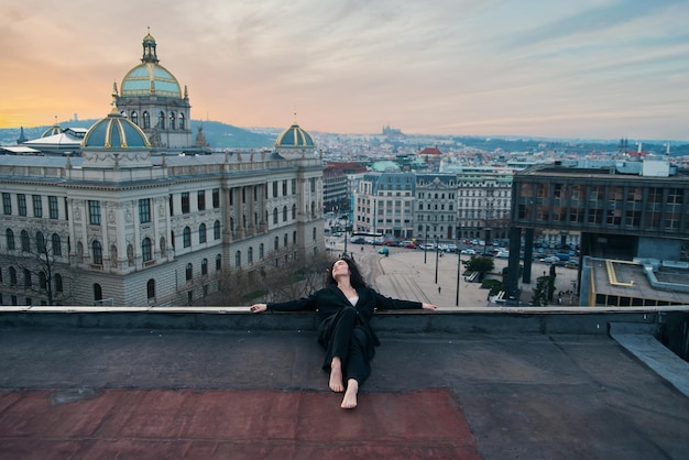 Foto una ragazza attraente con una maglietta bianca e un cardigan sul tetto