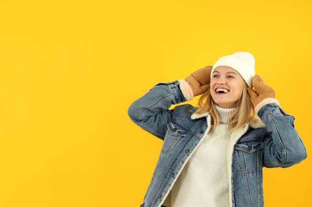 Attractive girl in winter clothes on yellow background.