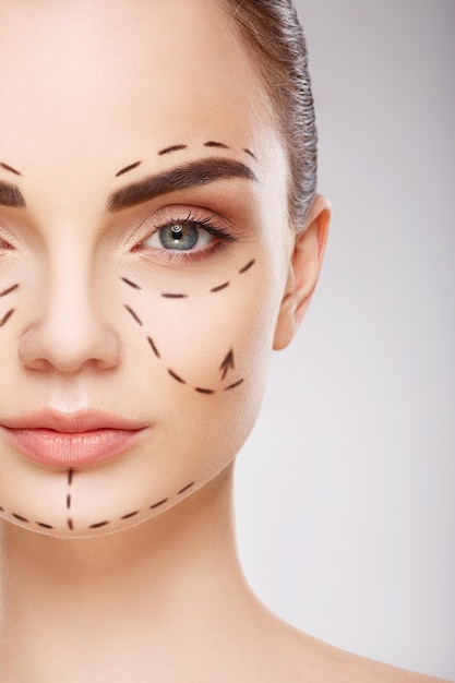 attractive girl with dark eyebrows at studio background with perforation lines on face, plastic surgery concept, close up portrait.