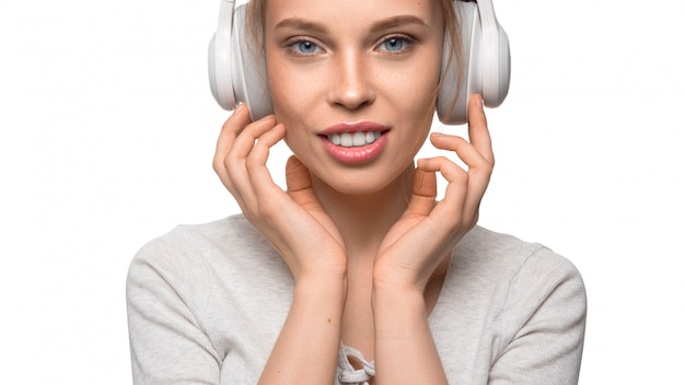 Attractive girl with headphones on white wall