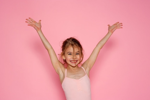 attractive girl with her hands up having fun on the pink wall