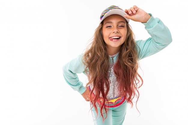 Attractive girl with long colored hair with a casual sports suit and a baseball cap on a white background