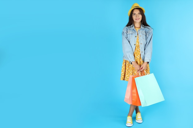 Attractive girl with multicolored paper bags on blue background.