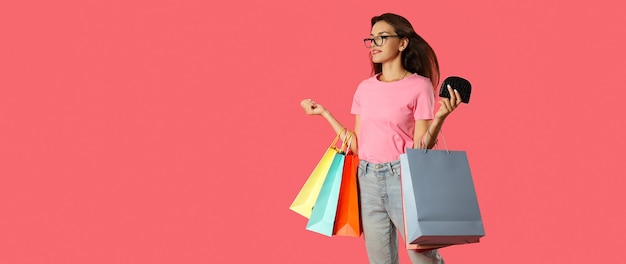 Attractive girl with multicolored paper bags on pink background.