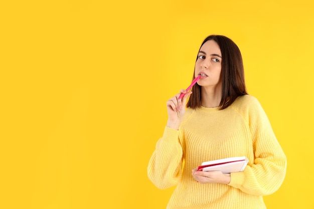 Photo attractive girl with notebook on yellow background