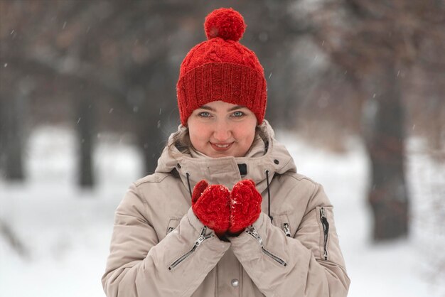 Attractive girl in wool red hat and mittens warms up in the winter outdoors Woman in comfortable clothes for winter walks