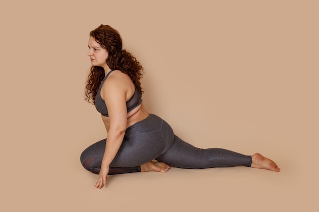 Attractive groomed fat obese plump woman doing sports stretch sitting half splits Spine and muscles Burning calories