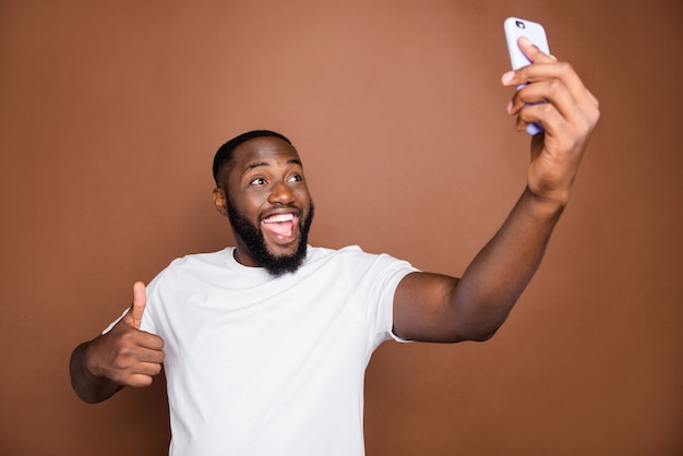 Attractive guy in casual clothes posing against the brown wall