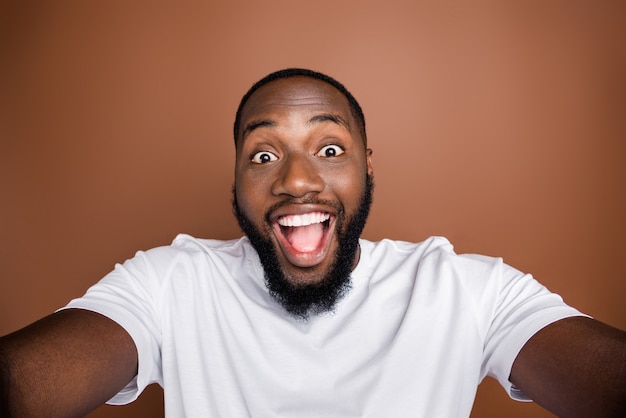 Attractive guy in casual clothes posing against the brown wall