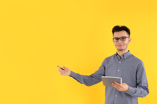 Attractive guy with notebook and pen on yellow background