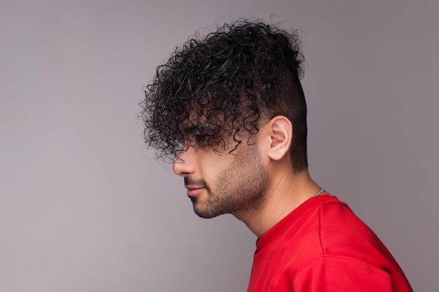 Attractive handsome bearded man with curly hair wearing jumper looking ahead showing his hairdo