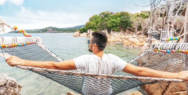 Attractive handsome young latino brunette man with a beard on a hammock on vacation