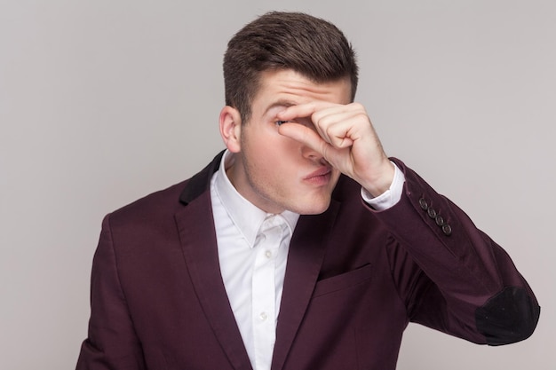 Attractive handsome young man keeps her finger near eyes showing small gesture peeping