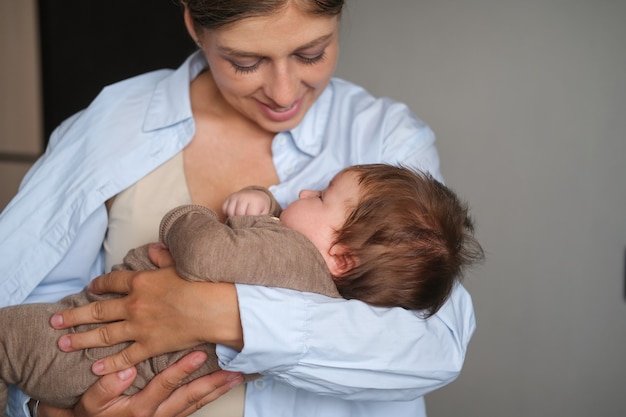 Foto madre felice attraente che tiene piccola neonata sorridente. allattamento bambino. famiglia felice. a casa. amore. dolce. tenerezza. goditi il tempo trascorso insieme. foto di alta qualità