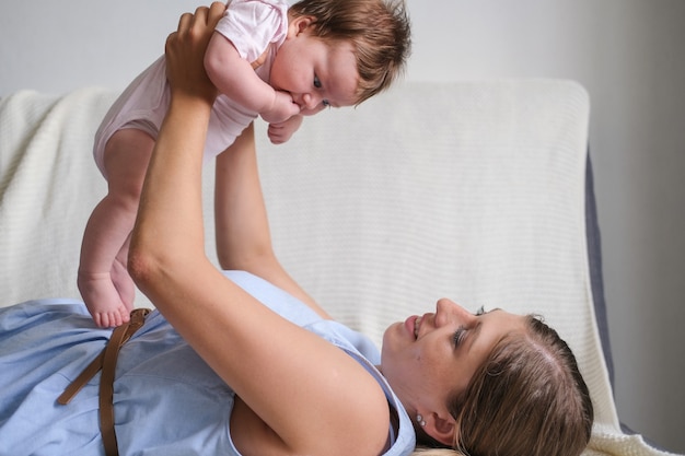 Le madri felici attraenti tengono, giocano con la piccola neonata. famiglia felice. godetevi il tempo insieme a casa. rallentatore. amore. dolce. tenerezza.