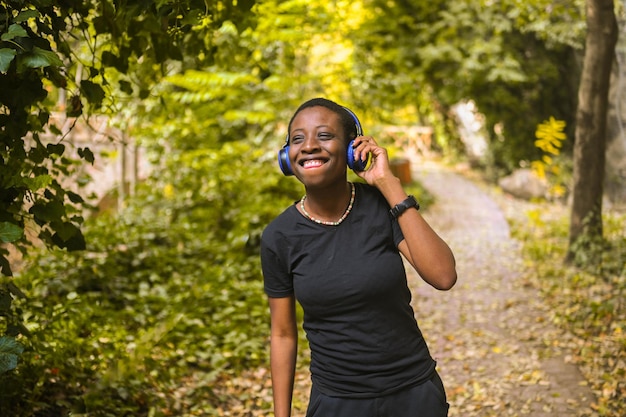 Attraente sorridenti giovani bellezza naturale dai capelli corti donna nera africana con cuffie blu