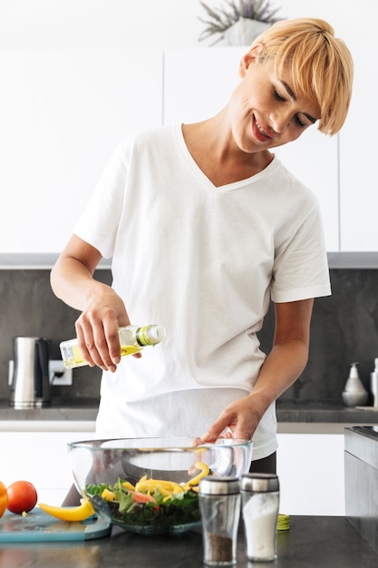 Attractive healthy woman cooking salad at the kitchen