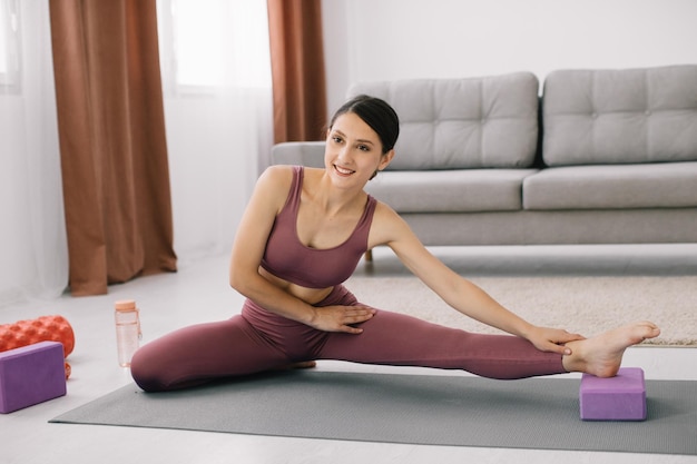 Привлекательная и здоровая молодая женщина делает упражнения во время отдыха дома