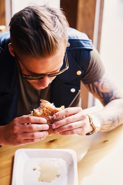 Photo attractive hipster dressed in leather jacket eating a vegan burger.