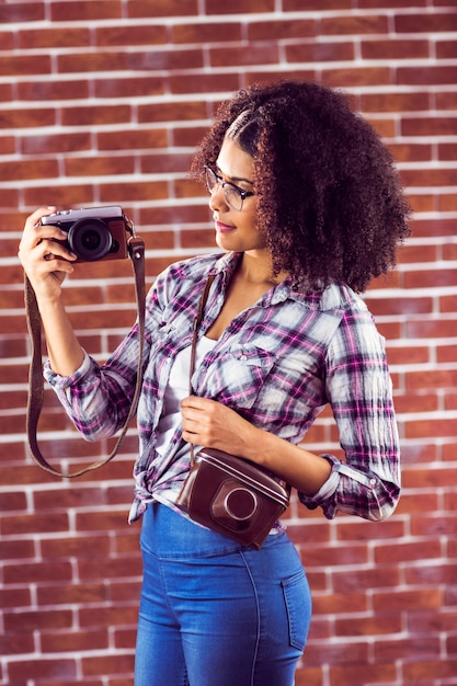 Attractive hipster holding camera and looking at it