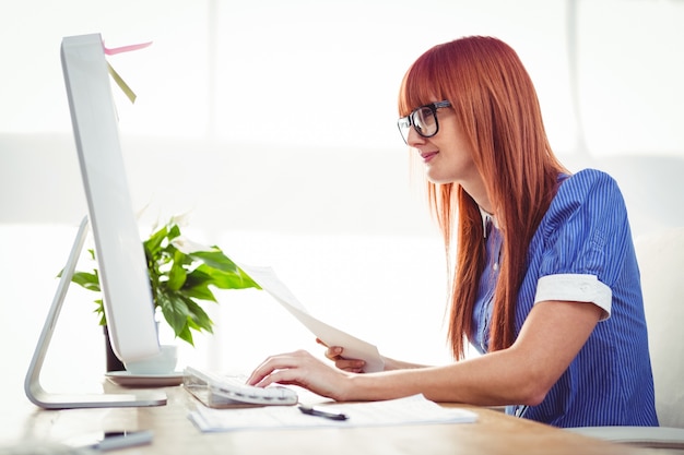 Attractive hipster woman with document typing on keyboard