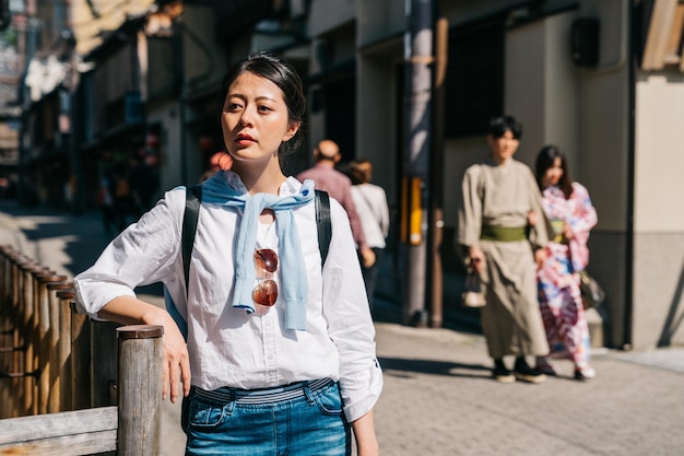 Foto signora attraente che fa affidamento sul corrimano e aspetta già la sua amica da molto tempo. incontri un ragazzo e una ragazza giapponesi che indossano un kimono tradizionale a piedi. stile di vita dei giovani giapponesi.