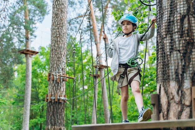 Attractive, little boy in insurance and a protective helmet stands on a suspension road. The child actively spends time