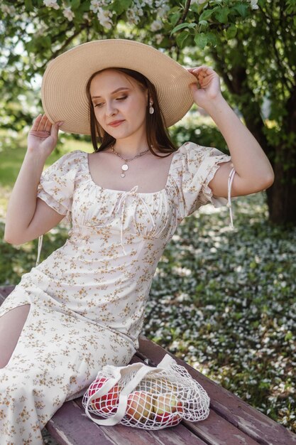 An attractive long-haired woman walks in the spring in the park of blooming apple trees            person