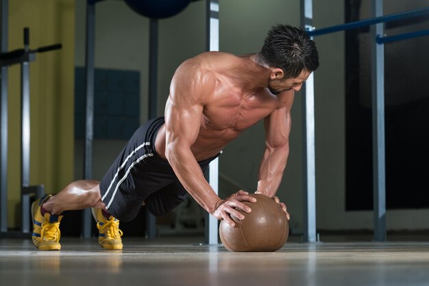 Attractive Male Athlete Performing PushUps On Medicine Ball