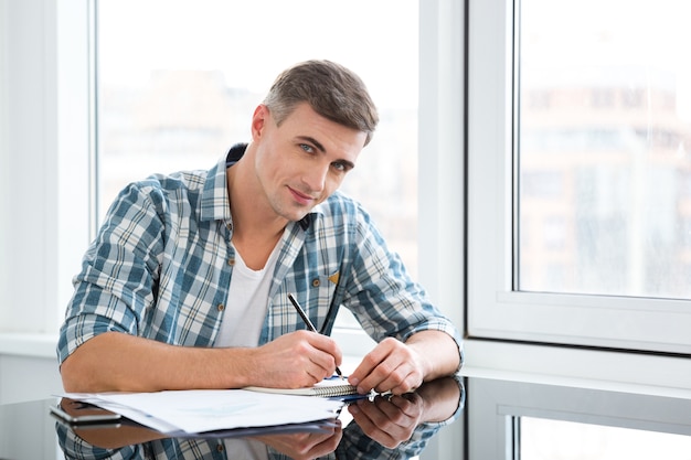 Attractive male in checkered shirt sitting and working in the office