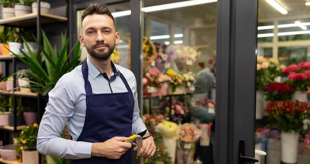 Fiorista maschio attraente accanto al frigorifero con fiori freschi freschi