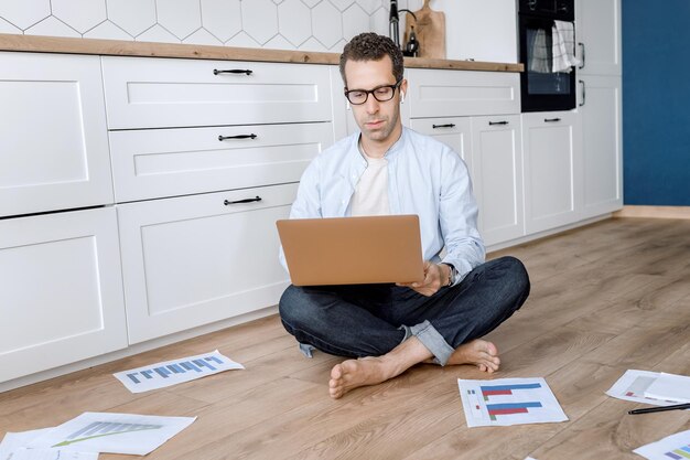 Attractive male freelancer using laptop waving to colleagues on video meeting smiling