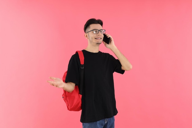 Attractive male student talking on the phone against pink background